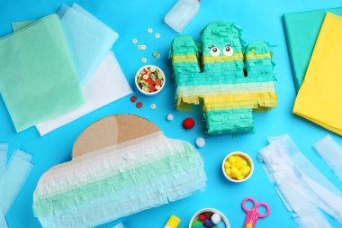 Karton kaktüslü düz kompozisyon ve açık mavi arkaplanda bulut. Pinata diy