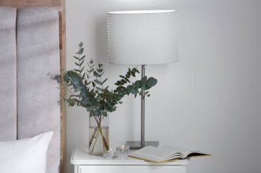 Güzel okaliptüs dalları ve yatak odasındaki komodinin üzerine kitap. İç tasarım