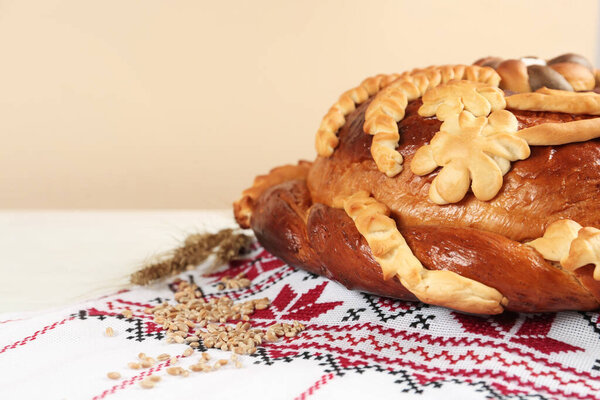 Rushnyk with korovai, wheat grains on table, space for text. Ukrainian bread and salt welcoming tradition