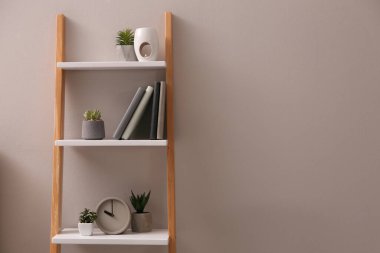 Gri duvarın yanındaki dekoratif merdivende bitkiler ve aksesuarlar, metin için yer.