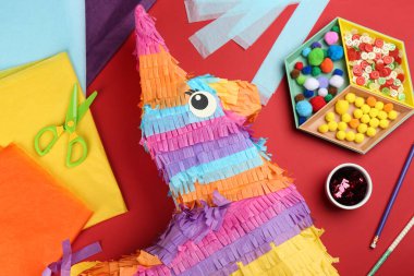 Kırmızı zemin üzerinde karton eşek ile düz kompozisyon yatıyordu. Pinata diy
