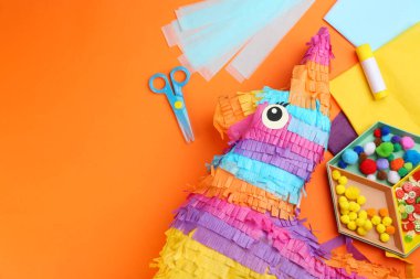 Turuncu arka planda karton eşekle düz kompozisyon, metin için boşluk. Pinata diy