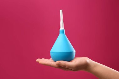 Pembe arka planda açık mavi lavman tutan kadın, yakın plan.