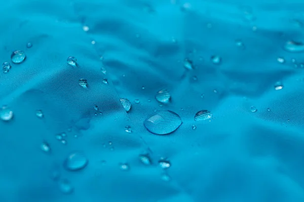 Light blue waterproof fabric with water drops as background, closeup