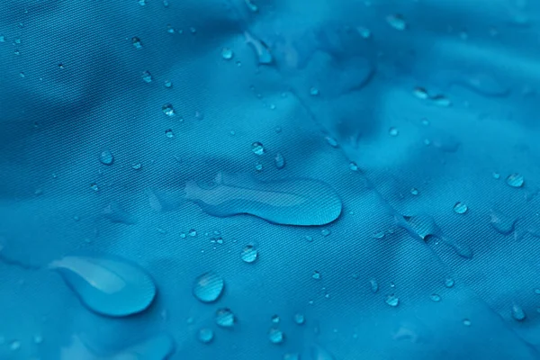 Light blue waterproof fabric with water drops as background, closeup