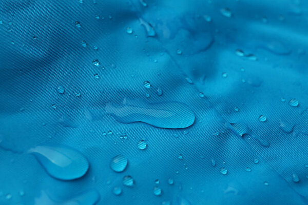 Light blue waterproof fabric with water drops as background, closeup