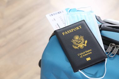 Pasaport, koruyucu maske ve mavi bavulda biletler. Karantina sırasında seyahat