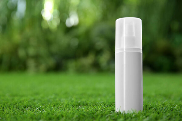 Бутылка спрея от насекомых на зеленой траве. Пространство для текста
