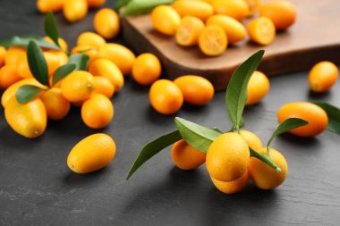 Taze kumkatlar ve yapraklar siyah masada.