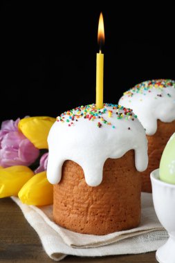 Geleneksel Paskalya pastaları ve siyah arka planda yanan bir mum.