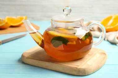 Limon dilimli sıcak çay ve açık mavi ahşap masada nane.