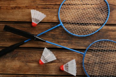 Raketler ve mekiklerin horozları ahşap masada, düz yatıyordu. Badminton ekipmanı