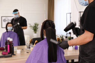 Profesyonel stilist, müşteriyle kuaförde çalışıyor. Coronavirus karantinası sırasında kuaför servisi