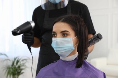 Müşteriyle kuaförde çalışan profesyonel stilist, yakın plan. Coronavirus karantinası sırasında kuaför servisi