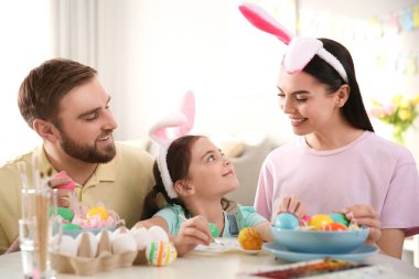 Mutlu aile, paskalya yumurtalarını kapalı bir masada boyuyor.