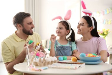 Mutlu aile, paskalya yumurtalarını kapalı bir masada boyuyor.