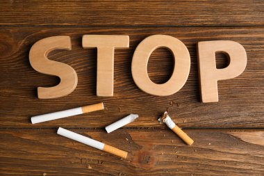 Kırılmış ve sigaranın tamamı kelimenin yanında. Ahşap masada dur, düz yat. Sigarayı bırakma kavramı