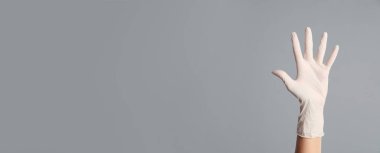 Doktor gri arka planda tıbbi eldiven giyiyor, yakın plan. Metin için alanı olan pankart tasarımı 