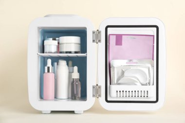 Bej arka planda cilt bakım ürünleriyle birlikte açık kozmetik buzdolabı