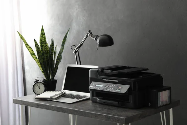 New modern printer and laptop on grey table in office