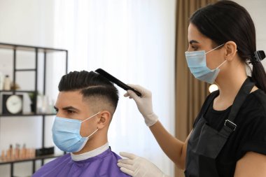 Müşteriyle kuaförde çalışan profesyonel stilist. Coronavirus karantinası sırasında kuaför servisi