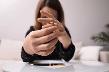 Kadın içeride masada alyansını çıkartıyor, ellerine odaklanıyor. Boşanma kavramı