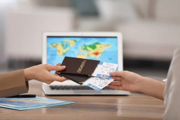 Travel agent giving tickets and passports to client in office, closeup