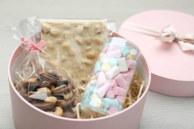 Çikolatalı hediye kutusu ve beyaz ahşap masada tatlılar, yakın plan.