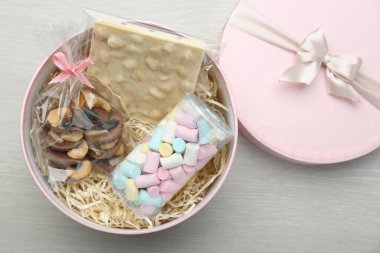 Çikolatalı hediye kutusu ve beyaz ahşap masada tatlılar, üst manzara.