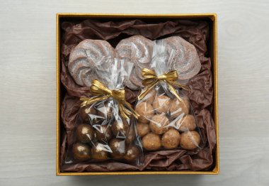 Çikolata ve şekerlerle dolu hediye kutusu beyaz ahşap masa, üst manzara.