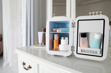 Beyaz makyaj masasında kozmetik ürünleri olan mini buzdolabı.