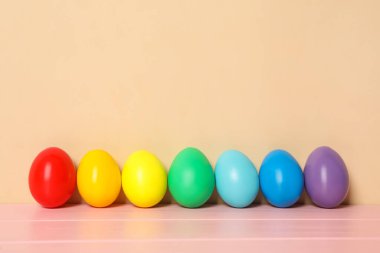 Pembe ahşap masadaki Paskalya yumurtaları bej arka plana karşı, metin için boşluk