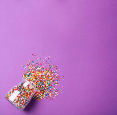 Rengarenk serpiştirilmiş kavanoz ve mor arkaplandaki yazı için boşluk, düz yatış. Şekerleme dekoru