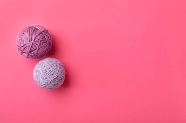 Pembe arka planda yumuşak renkli yün iplikler, düz yatış. Metin için boşluk