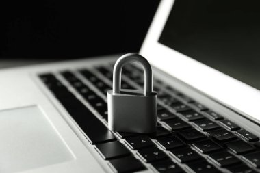 Karanlık arka planda metal kilit ve dizüstü bilgisayar, yakın plan. Siber güvenlik kavramı