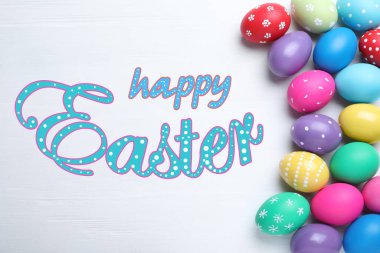 Mutlu Paskalyalar. Parlak boyalı yumurtalar beyaz ahşap masada, düz yatıyordu.  