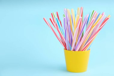 Açık mavi arkaplanda renkli plastik pipetler, metin için boşluk