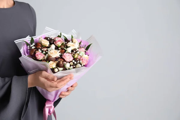 Woman with beautiful food bouquet on light grey background, closeup. Space for text