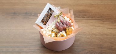 Tahta masada çikolatalı ve şekerli bir hediye kutusu.