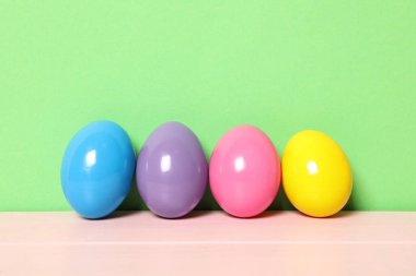 Pembe ahşap masadaki paskalya yumurtaları yeşil arka plana karşı, metin için boşluk