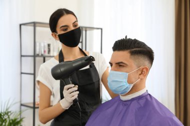 Müşteriyle kuaförde çalışan profesyonel stilist. Coronavirus karantinası sırasında kuaför servisi