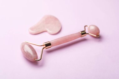 Pembe arka planda doğal yüz silindiri ve gua sha aracı
