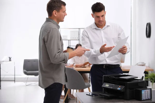 Employees near new modern printer in office