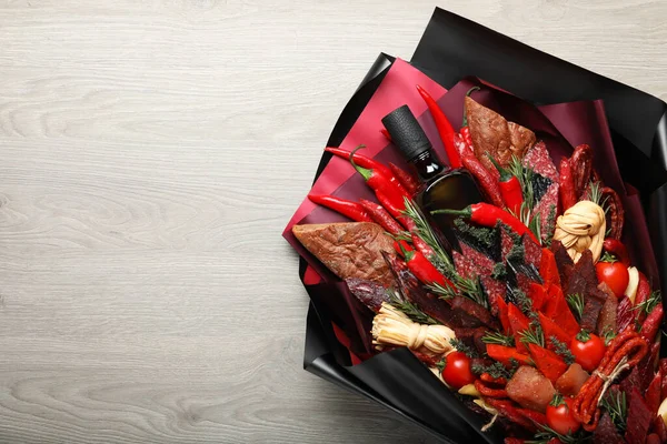 Beautiful edible bouquet with meat, cheese and vegetables on wooden table, top view. Space for text