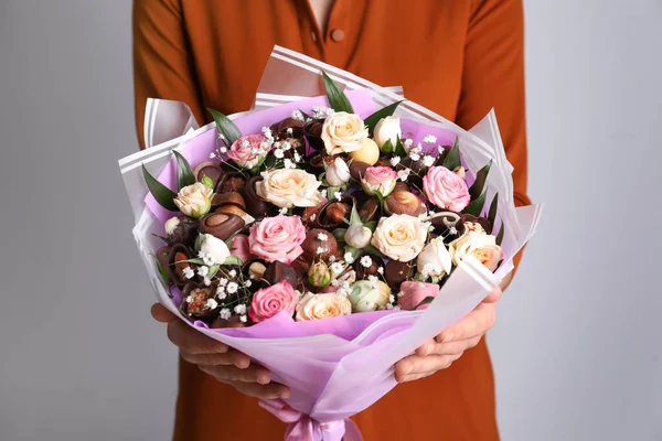 Woman with beautiful food bouquet on light grey background, closeup