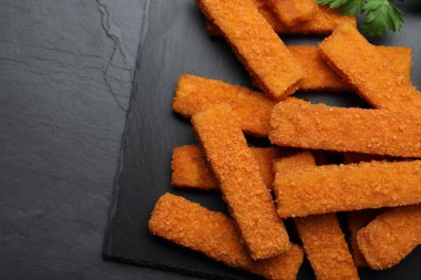 Siyah masada servis edilen taze ekmekli balık kroketleri.