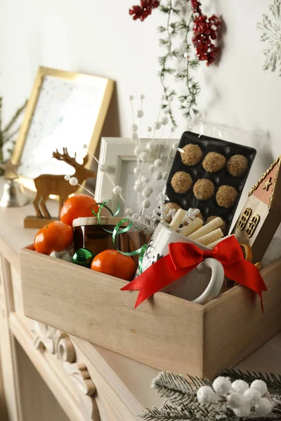 Crate with gift set and Christmas decor on mantelpiece