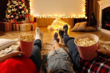 Patlamış mısırlı aile Noel için dekore edilmiş odada projeksiyon ekranında film izliyor, yakın plan. Ev TV ekipmanları