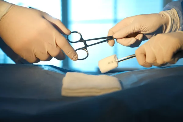 Professional surgeons with instruments performing operation in clinic, closeup