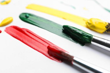 Beyaz arka planda farklı boya ve darbelerle fırçalar, yakın plan